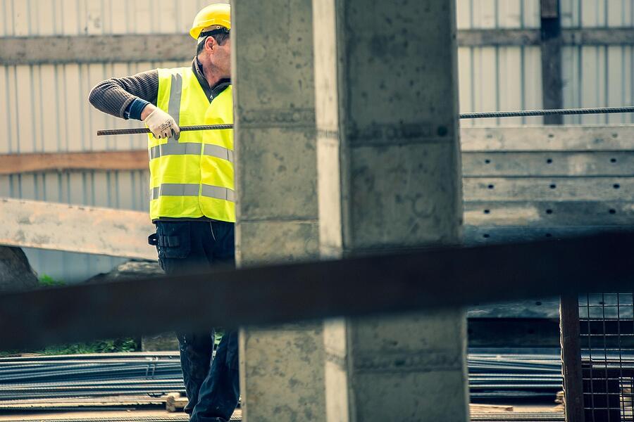 A worker in a high visibility vest beside a concrete column